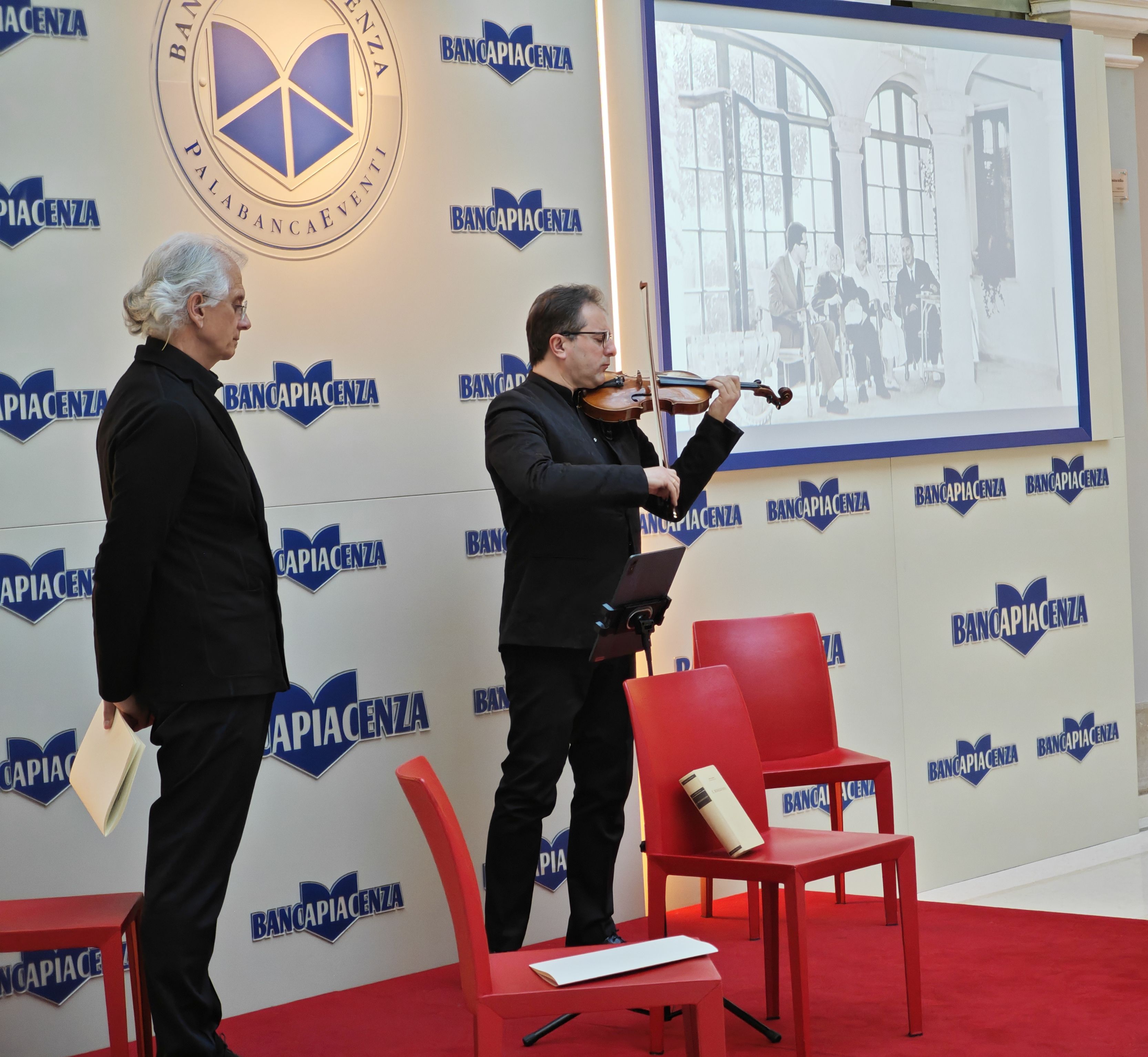 Finazzer Flory e il maestro Matteo Fedeli. Sullo sfondo la foto della visita di Sforza a Einaudi nel